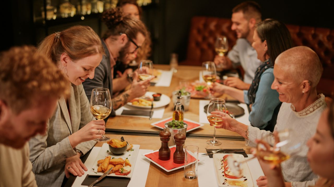 a group of people setting at restaurant, for the article Mastering English Phrases for Restaurant Adventures.