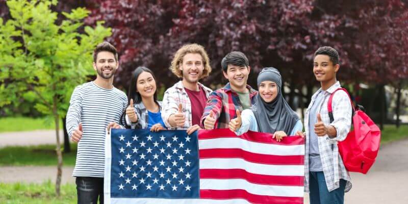 Group of non-native English speakers standing behind the USA flag, showcasing their journey to master the American accent from zero to fluency.
